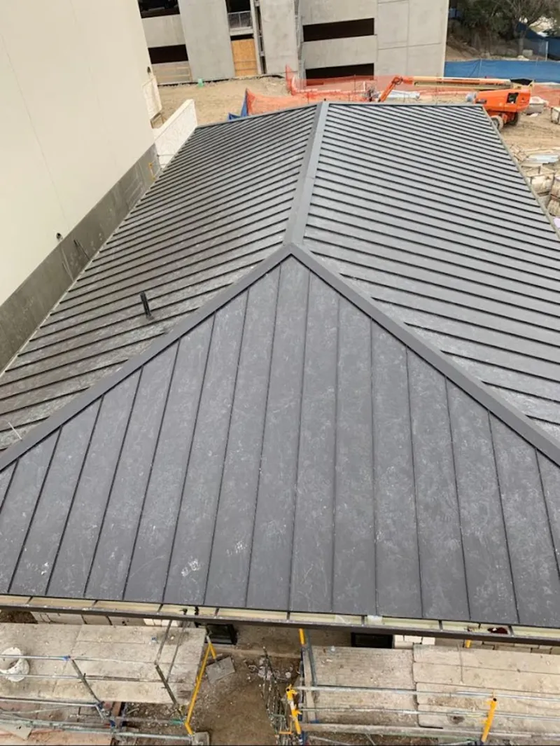 Commercial metal roof construction with crane equipment in Spring